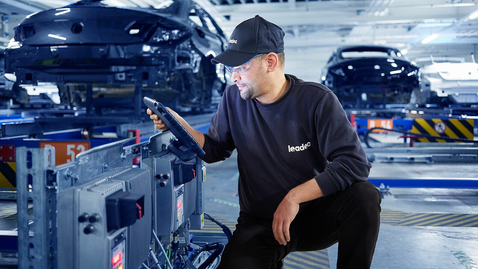 A Leadec employee configures an inverter at a conveyor belt.