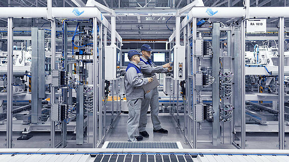 Two Leadec employees checking the control panel at an automatic station.